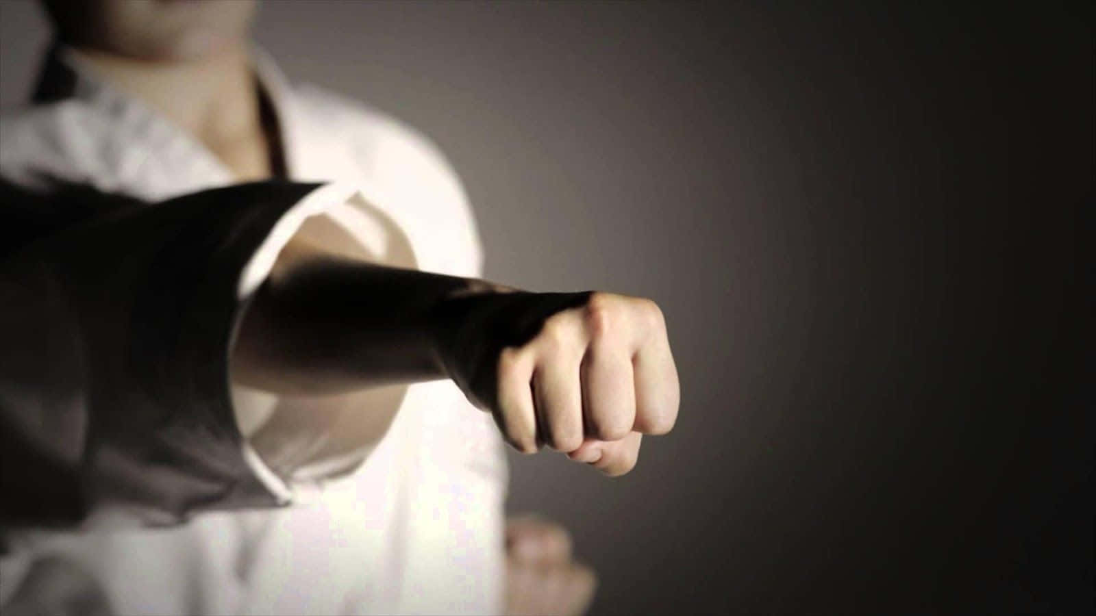 A Person In A White Karate Uniform Is Pointing His Finger