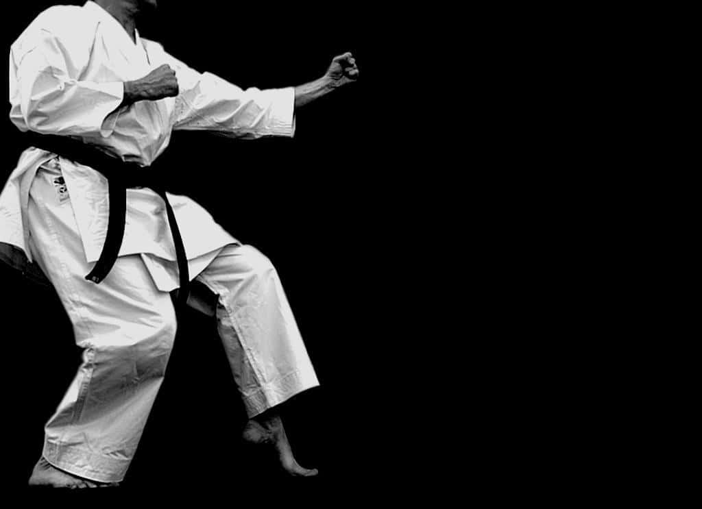 A Man In Karate Gear Doing A Kick