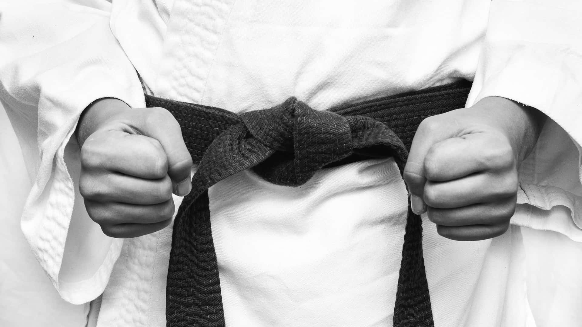 A Person Is Holding A Black Belt