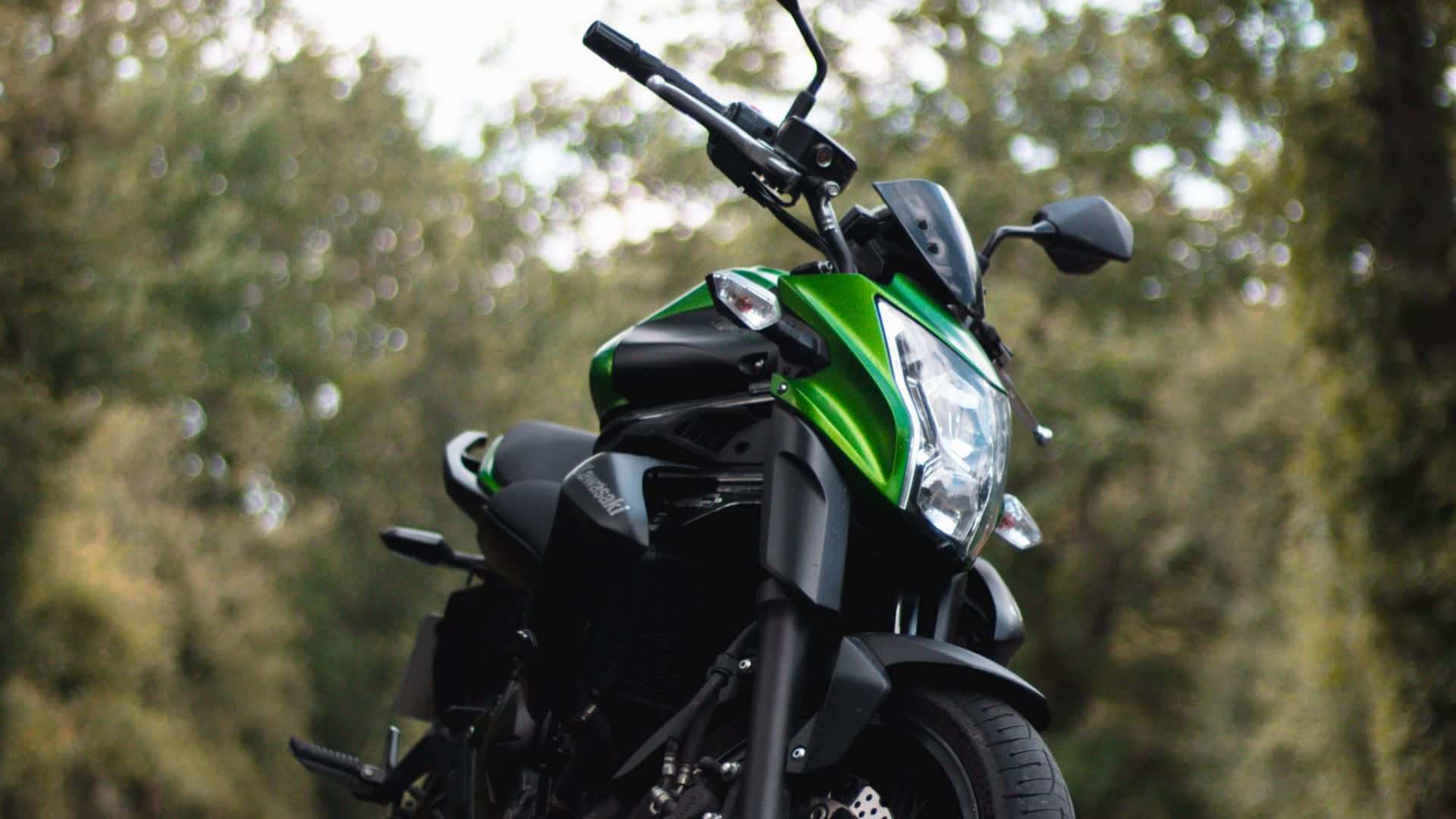 A Green And Black Motorcycle Parked On A Road Wallpaper