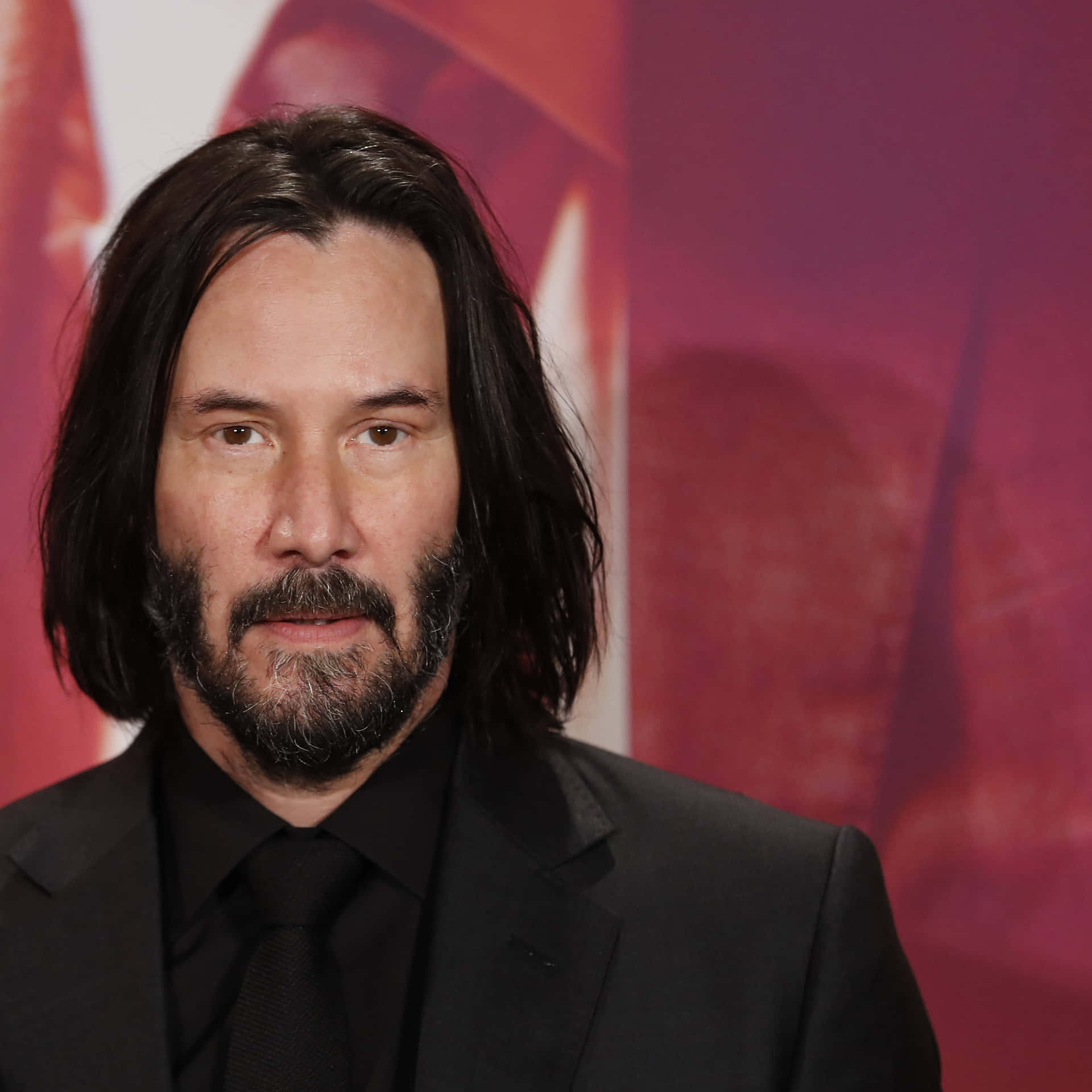 Keanu Reeves smirking in a stylish outfit