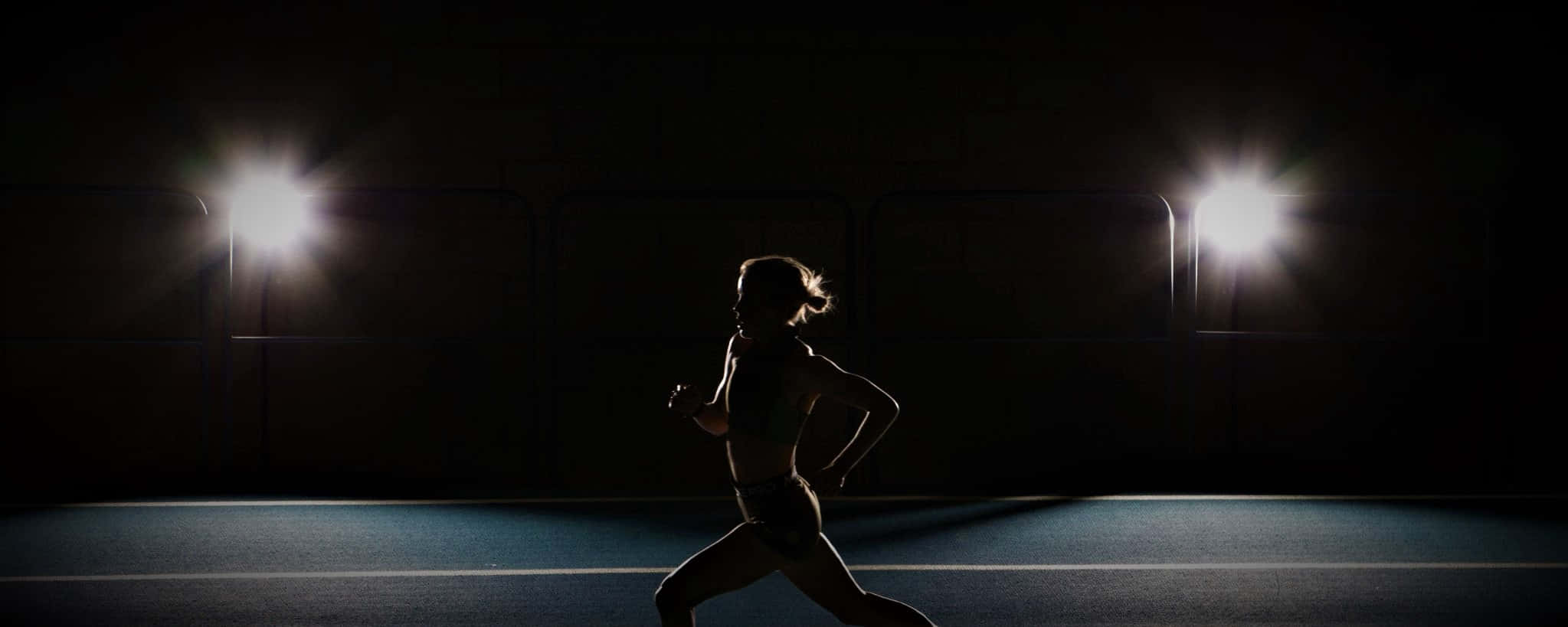 A Woman Running In The Dark On A Track Wallpaper
