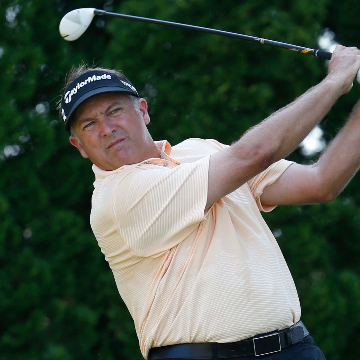 Professional golfer Ken Duke hits a strong swing on the fairway Wallpaper