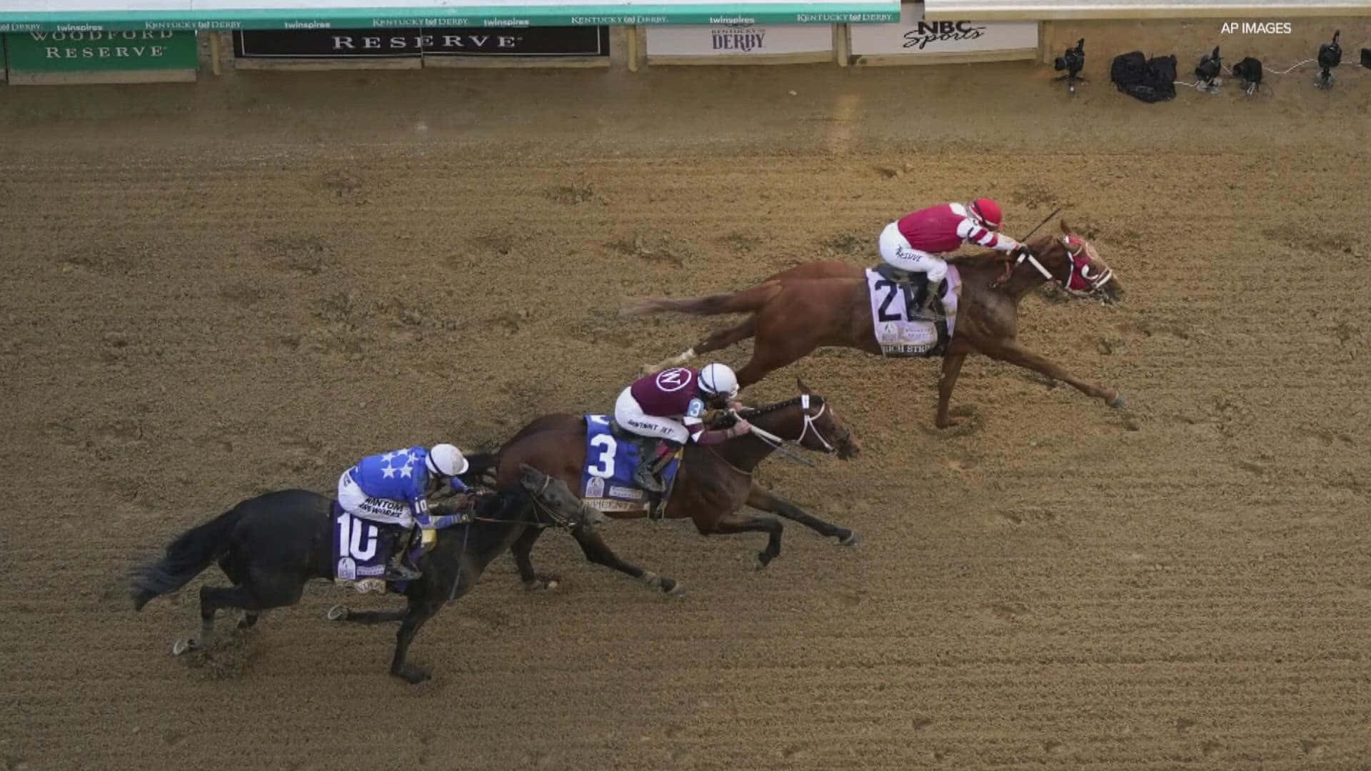 Tre heste konkurrerer på en dirt track