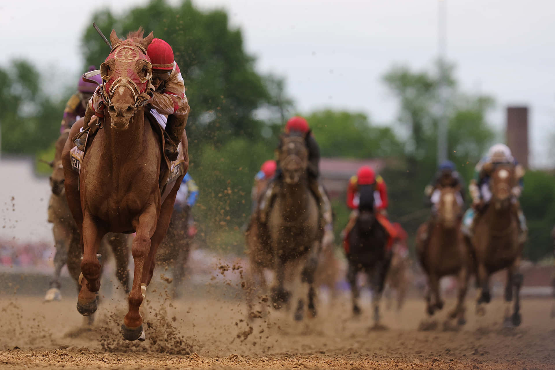 A Group Of Jockeys Are Racing Horses On A Dirt Track