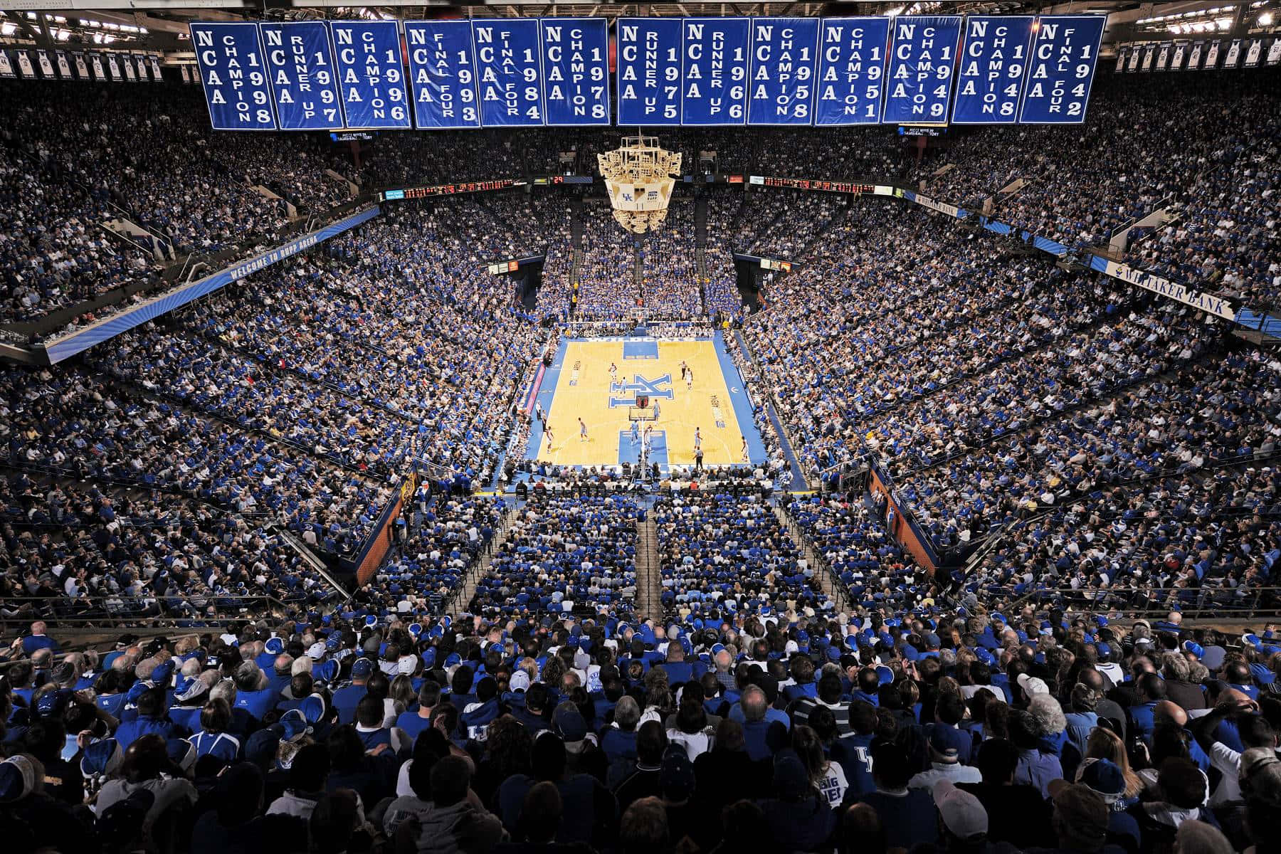 Et basketball spil i et stort arena med blå og hvide fans Wallpaper