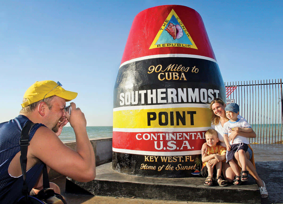 A Family Is Taking A Picture Of The Southernmost Point