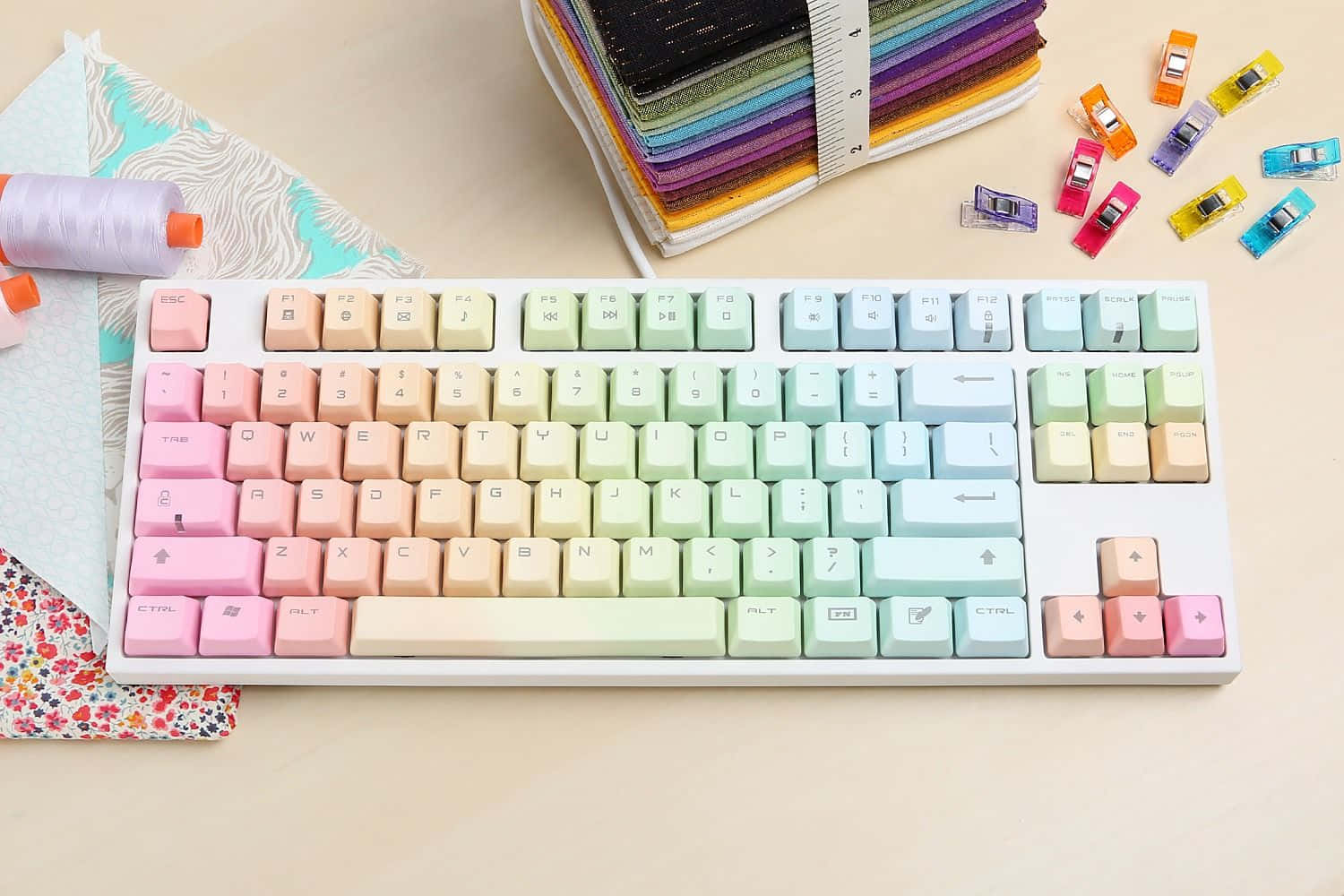 A Rainbow Colored Keyboard With Sewing Supplies On It