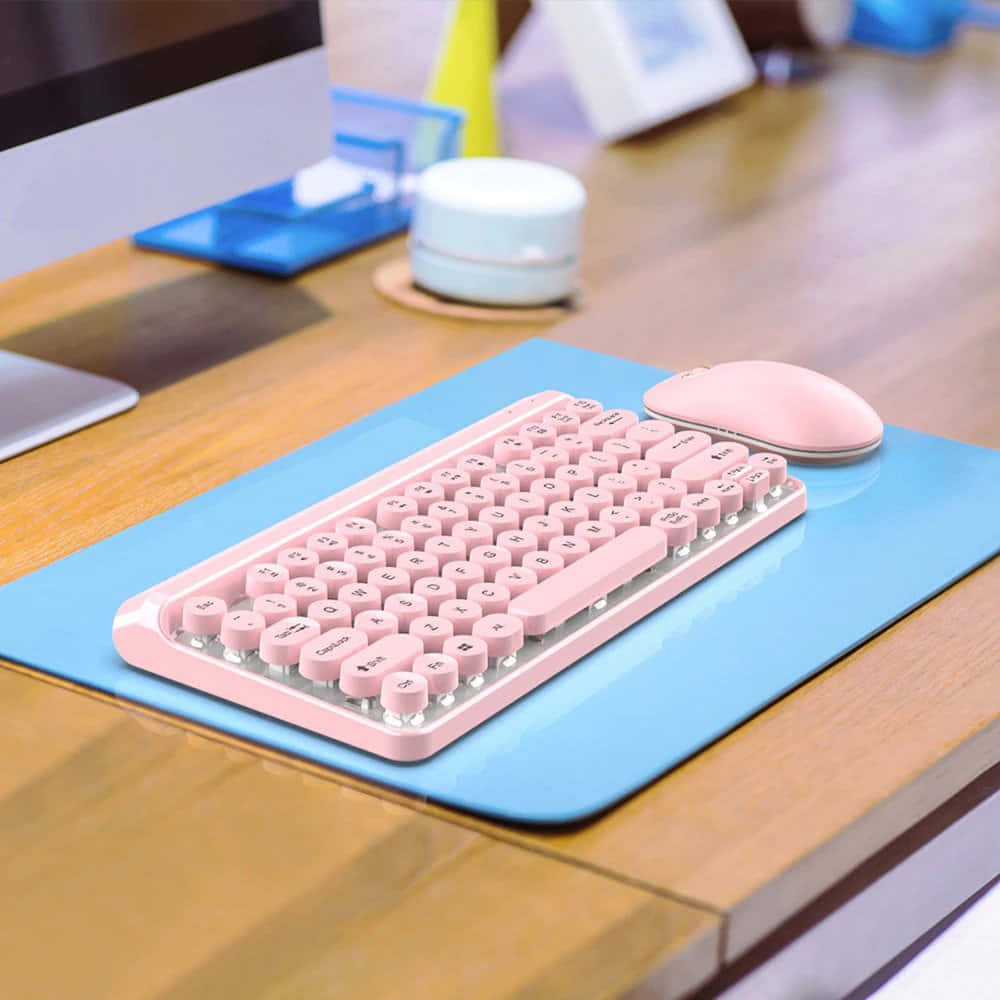 A Pink Keyboard On A Desk With A Mouse