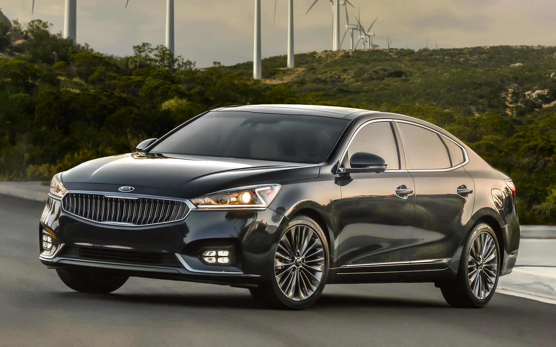 Sleek Kia Cadenza cruising on a scenic highway Wallpaper