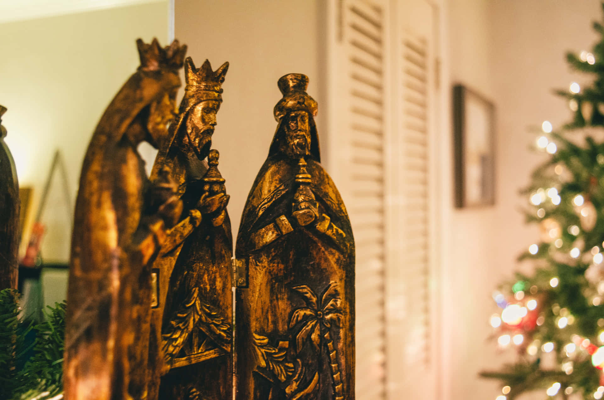 A Wooden Statue Of The Nativity In Front Of A Christmas Tree