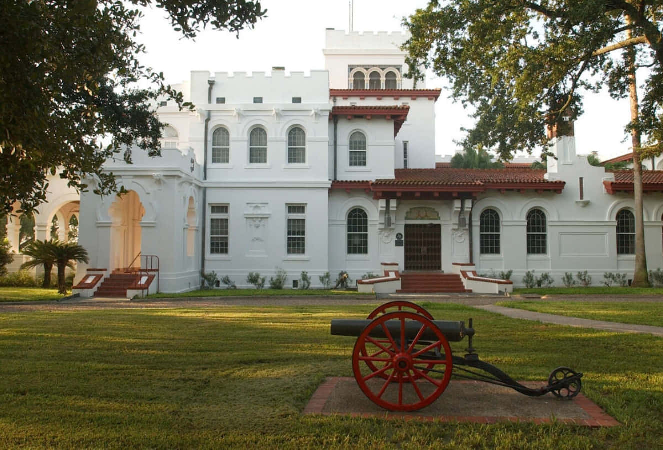 A Large White House With A Cannon In Front Of It