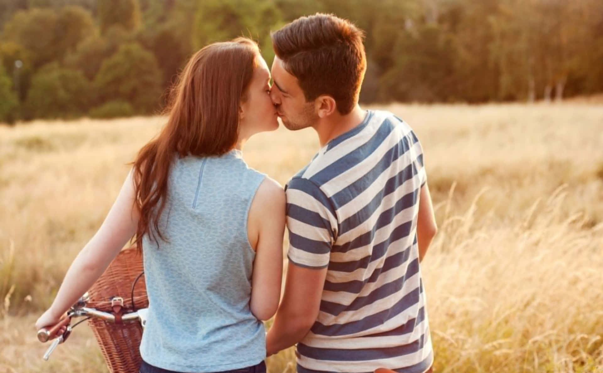 Einjunges Paar Küsst Sich Auf Einem Feld Mit Einem Fahrrad.