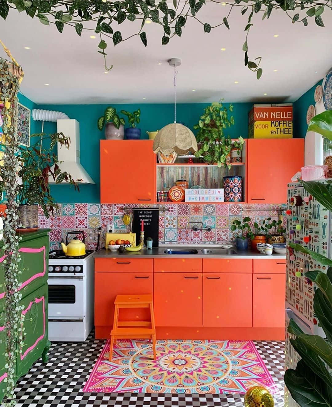 A Colorful Kitchen With Bright Orange Cabinets And A Colorful Floor