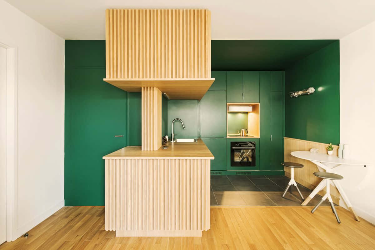 A Green Kitchen With Wooden Cabinets And A Wooden Floor