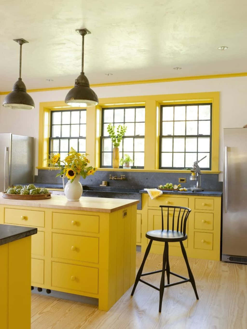 A Yellow Kitchen With Black Counter Tops And Wooden Floors