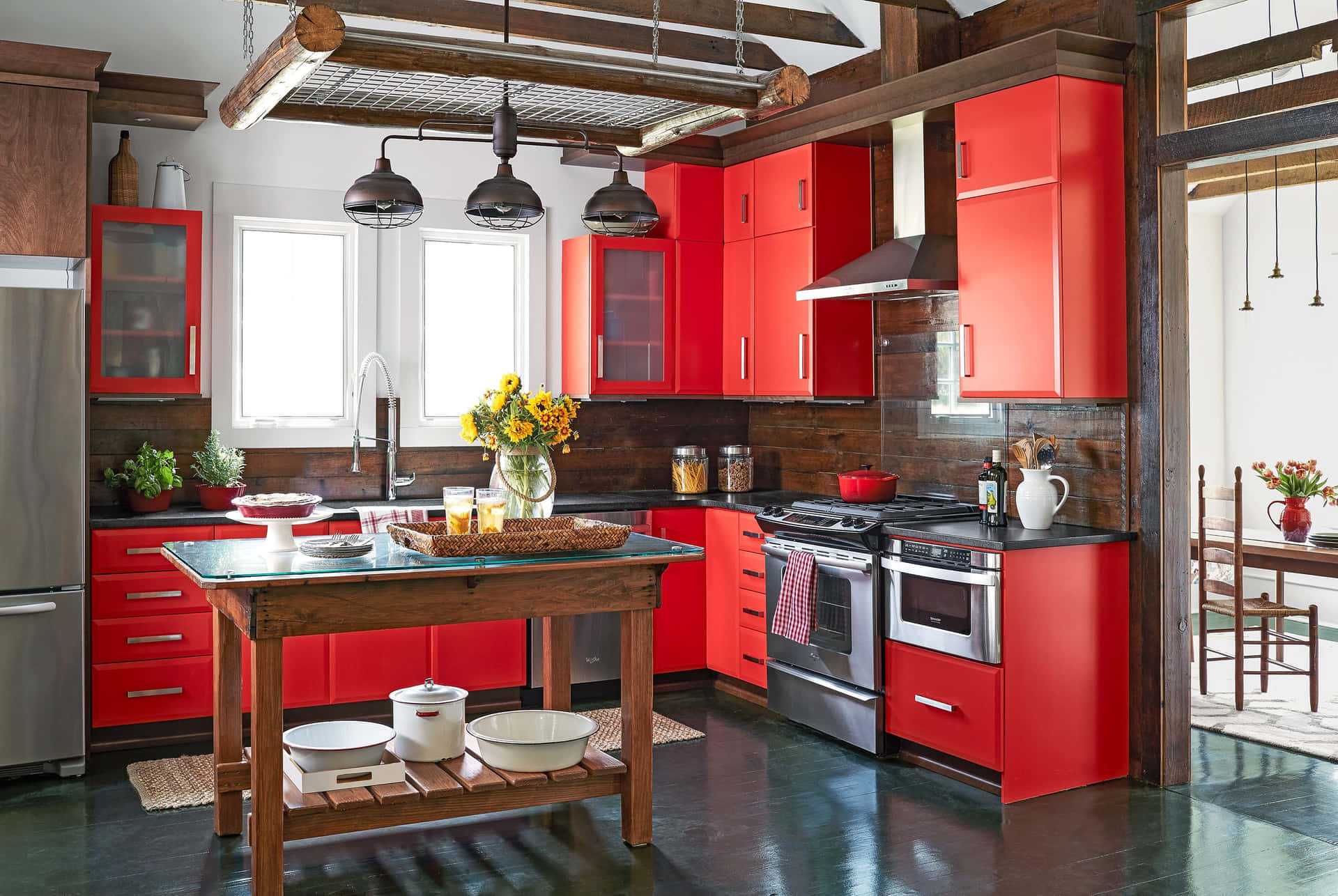 A Kitchen With Red Cabinets And A Wooden Table