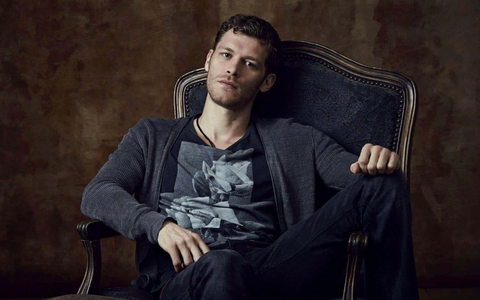 Klaus Mikaelson Posing On A Chair Wallpaper