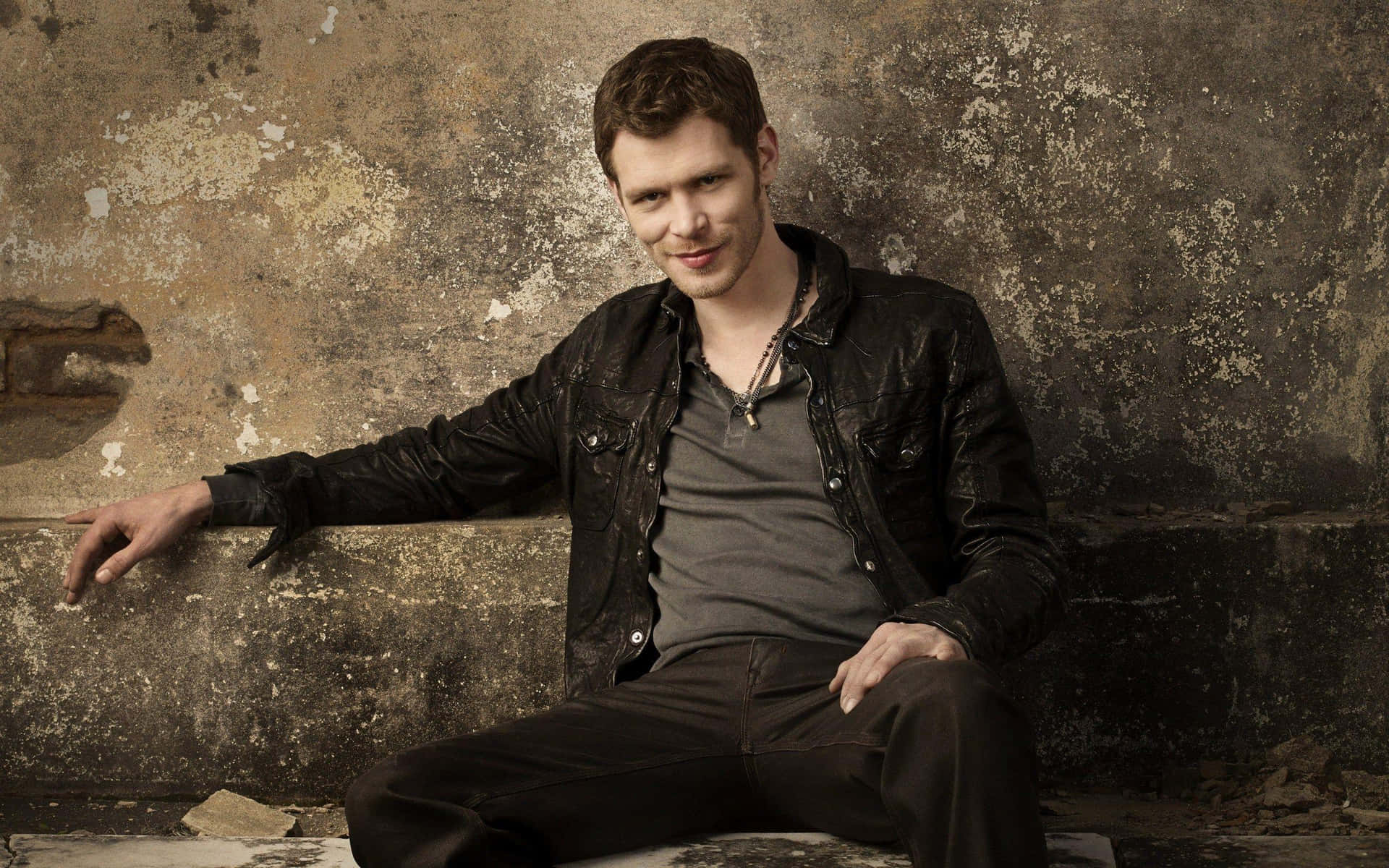 Klaus Mikaelson Sitting Against Concrete Wall Wallpaper