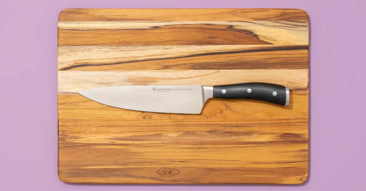 A Knife On A Cutting Board On A Purple Background