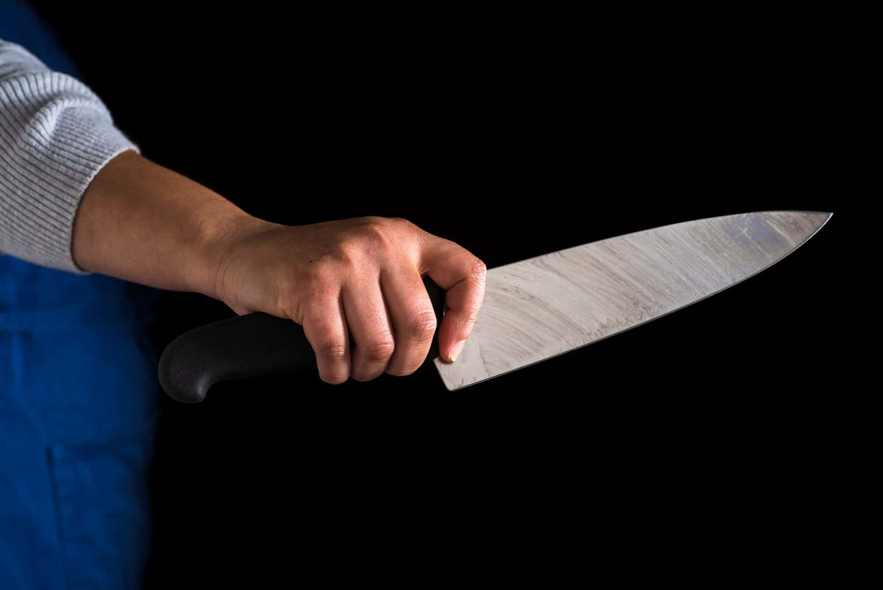 A Person Holding A Knife On A Black Background