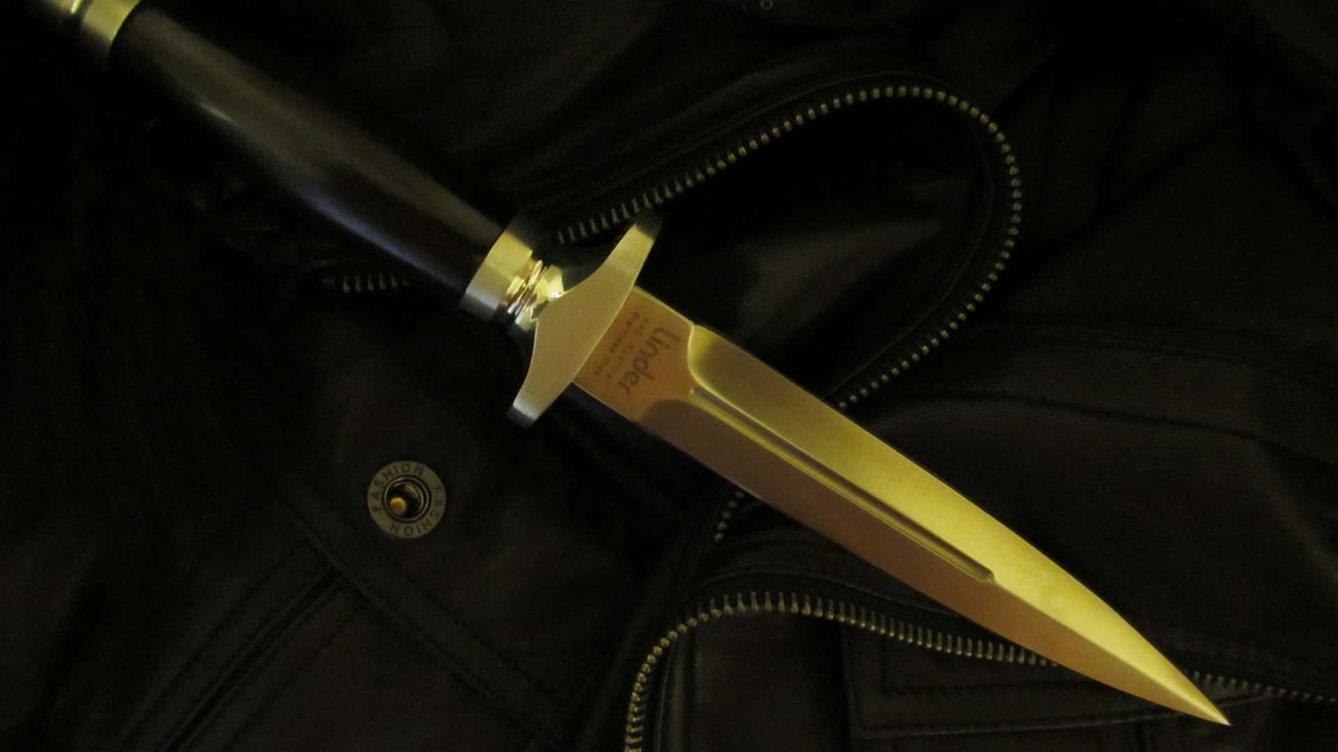 A Gold Knife Is Sitting On A Leather Jacket