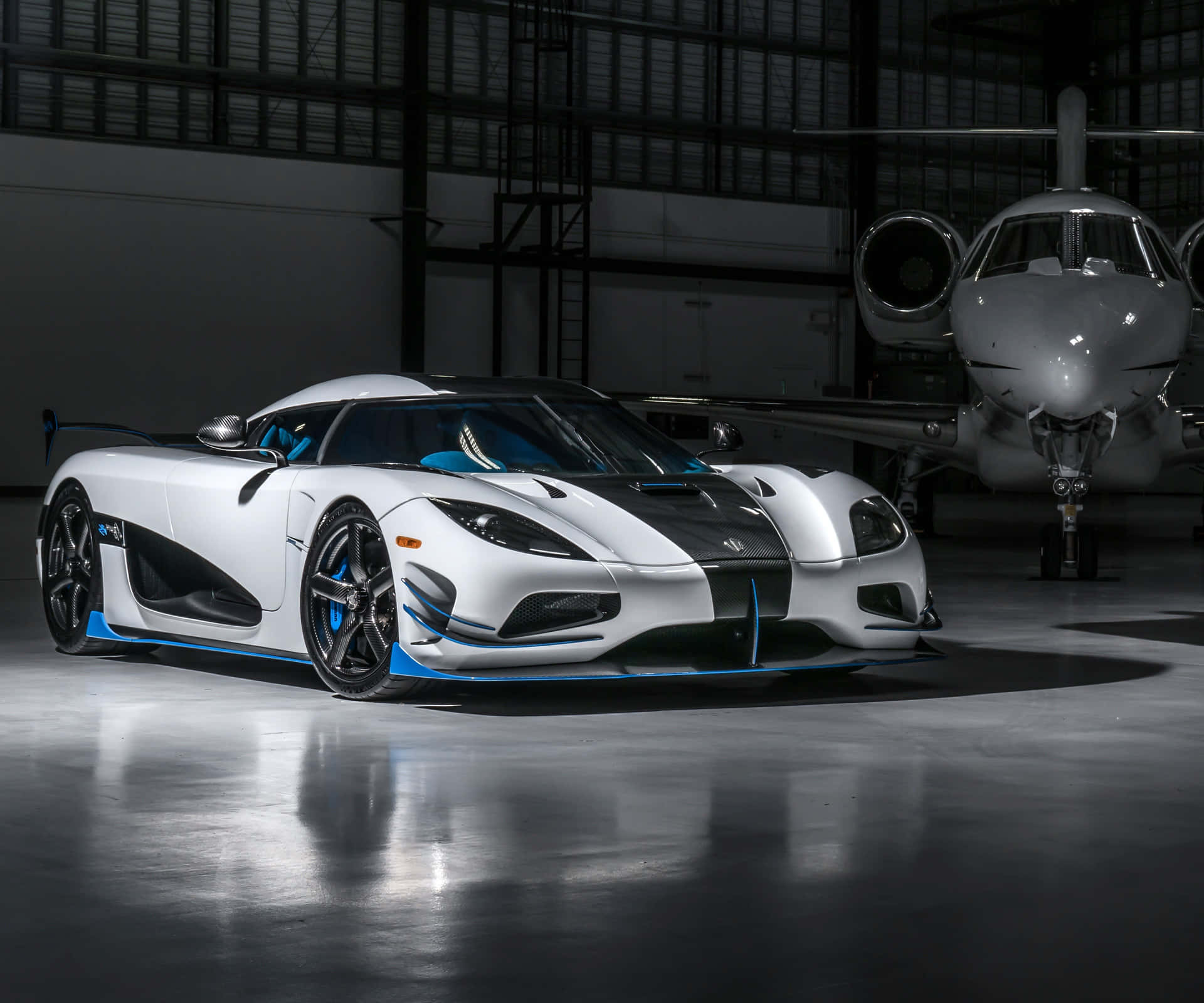 A White And Blue Sports Car Is Parked In Front Of A Plane Wallpaper