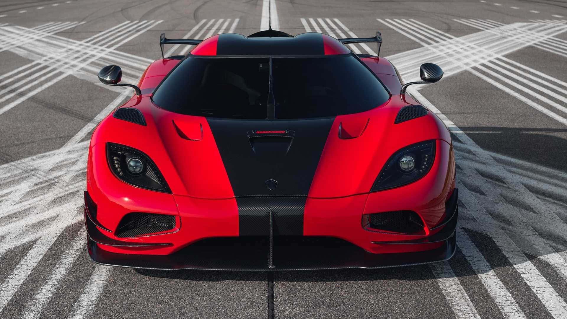 A Red And Black Sports Car Is Parked On An Asphalt Runway Wallpaper