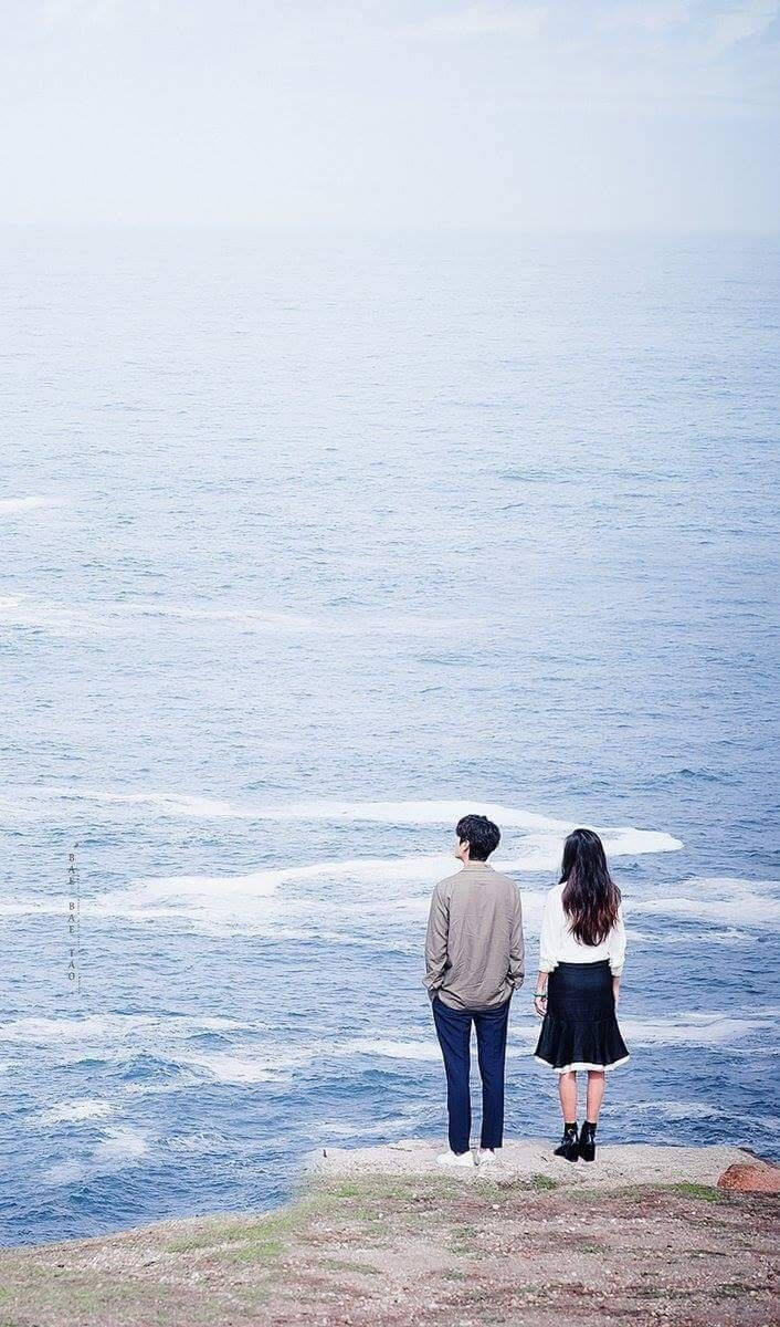 Korean Couple Standing Near The Ocean Wallpaper