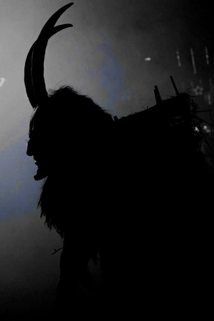 A Silhouette Of A Demon With Horns On His Head Wallpaper