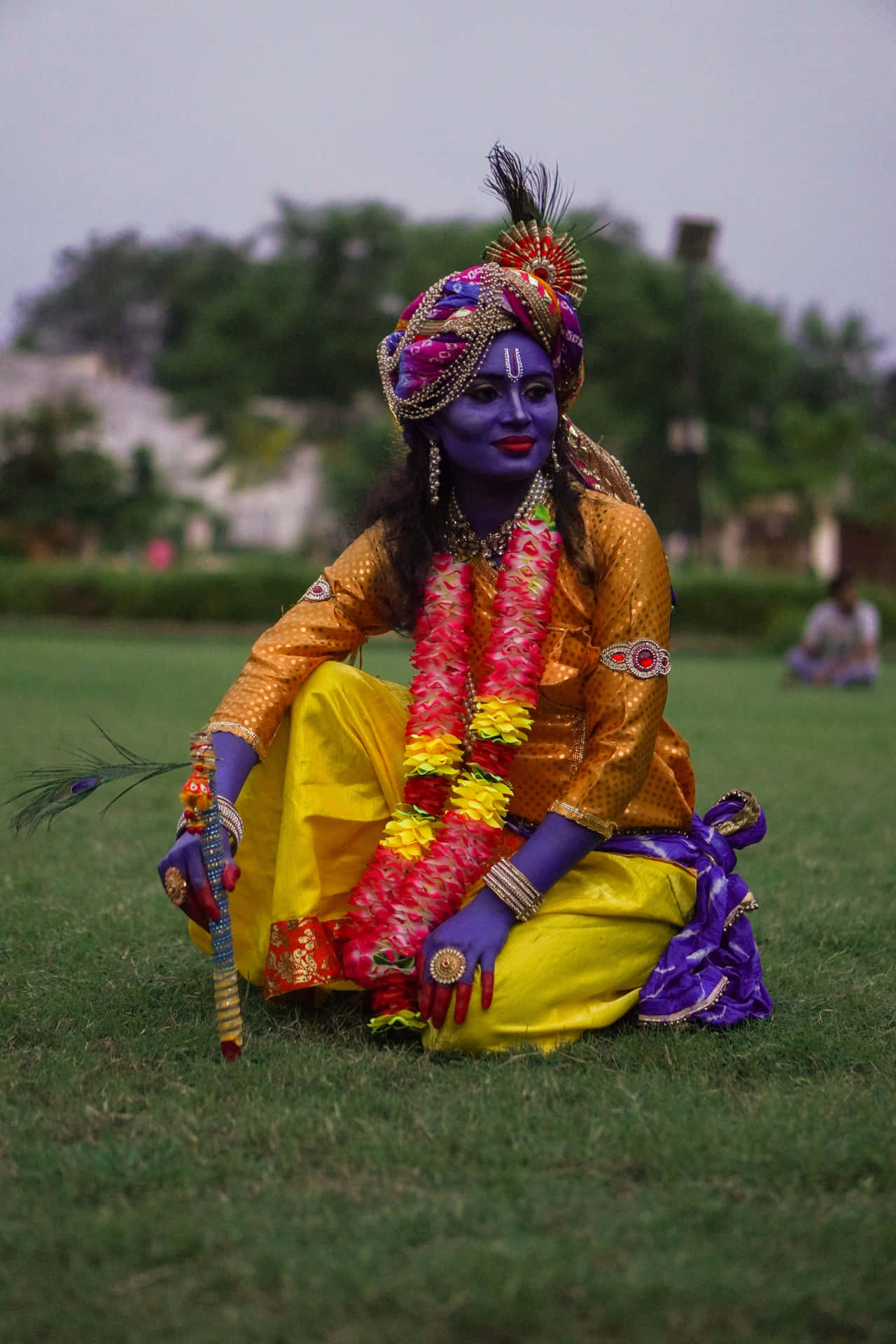 A Man In A Colorful Costume Sitting On The Grass