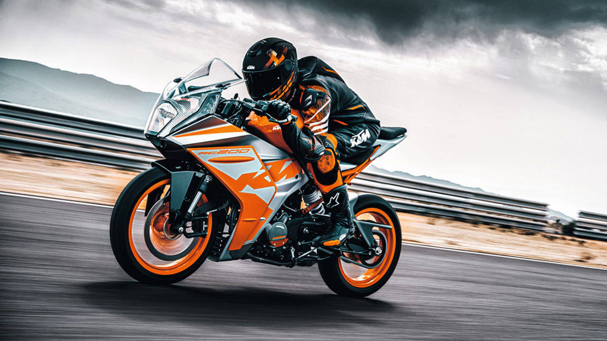 Download Ktm Rc 200 With Cyclist Wallpaper | Wallpapers.com