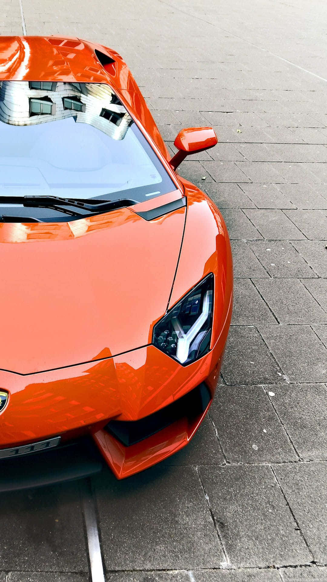 En orange sportsbil er parkeret på gaden. Wallpaper