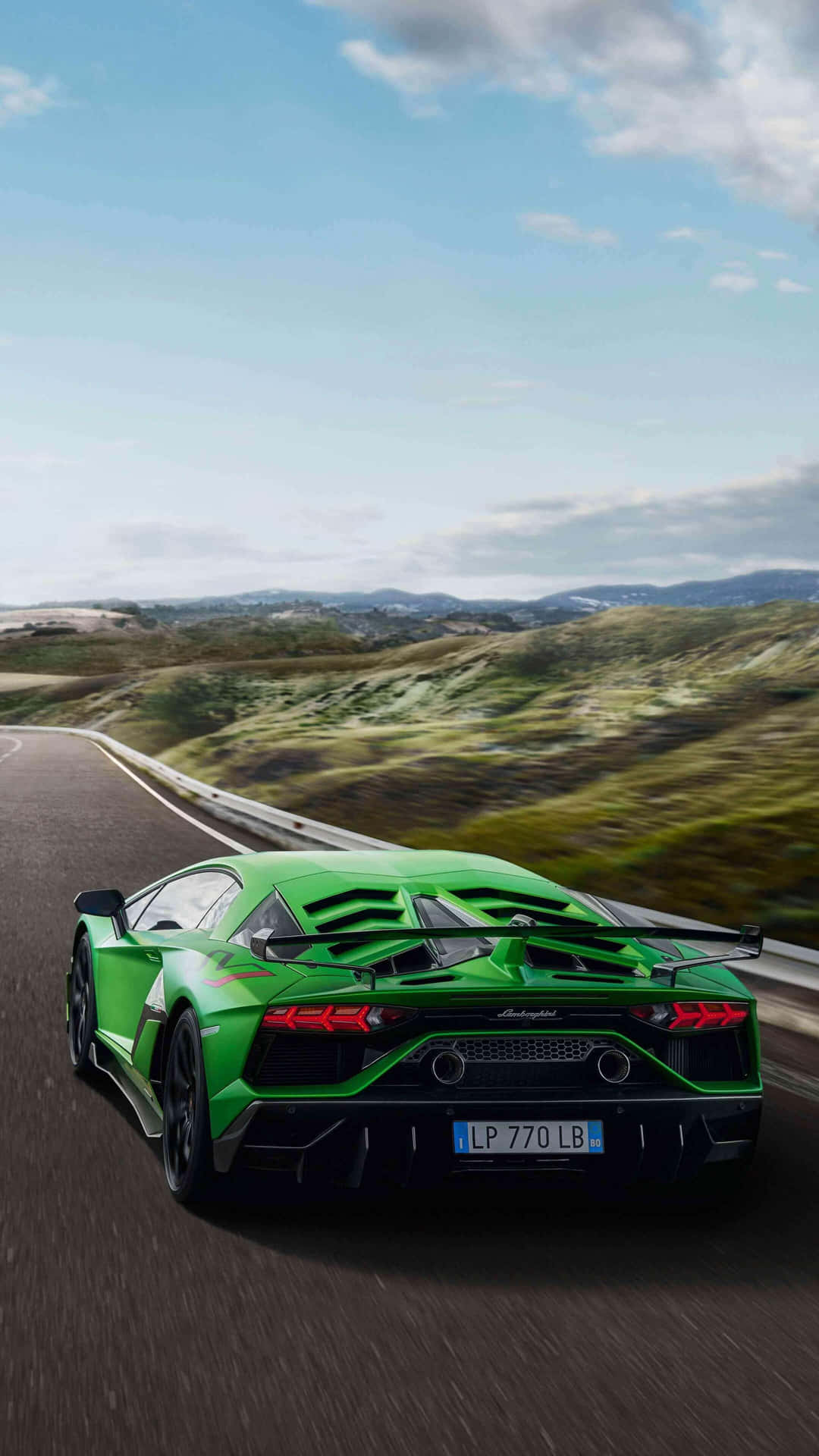 The Green Lamborghini Huracan Is Driving Down A Road Wallpaper