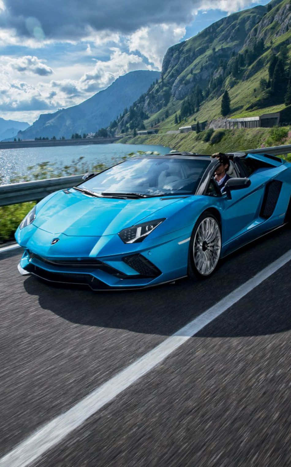 The Blue Lamborghini Spyder Is Driving Down The Road Wallpaper