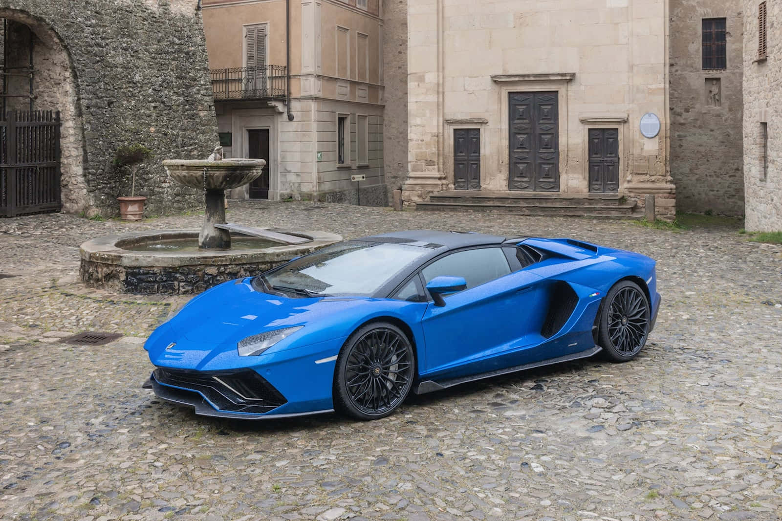 Den blå Lamborghini Huracan er parkeret foran en stenbygning.