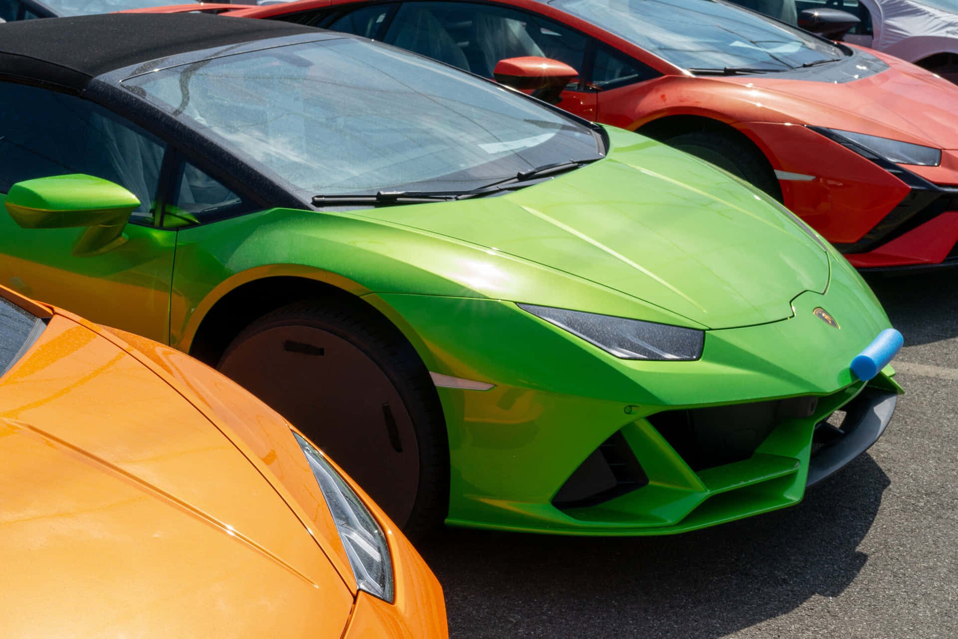 En række farverige sportsbiler parkeret på en parkeringsplads