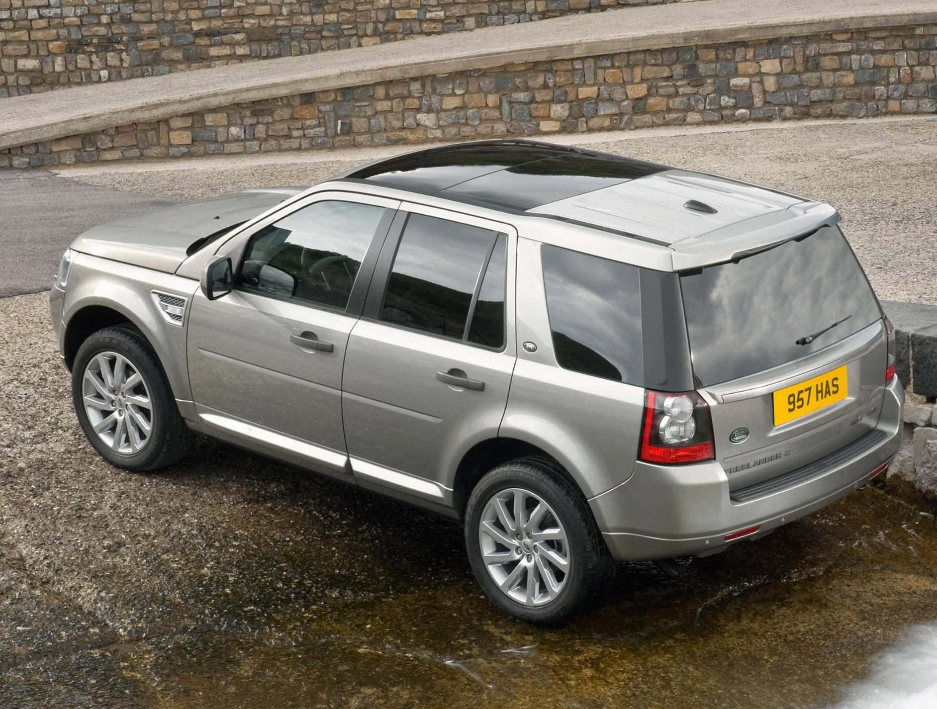 A Majestic Land Rover Freelander Parked by a Forest Wallpaper