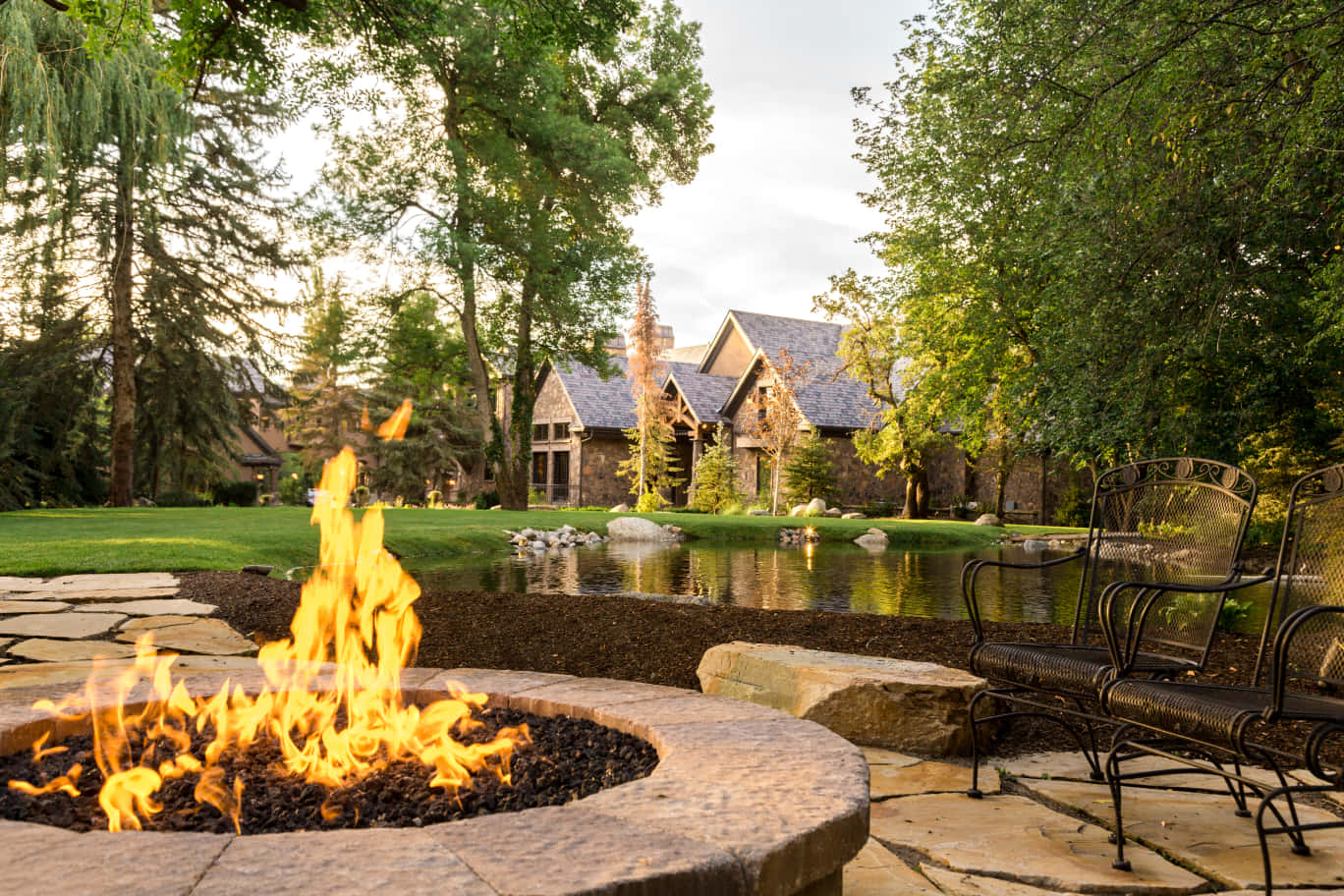 A Fire Pit In A Backyard With A Pond