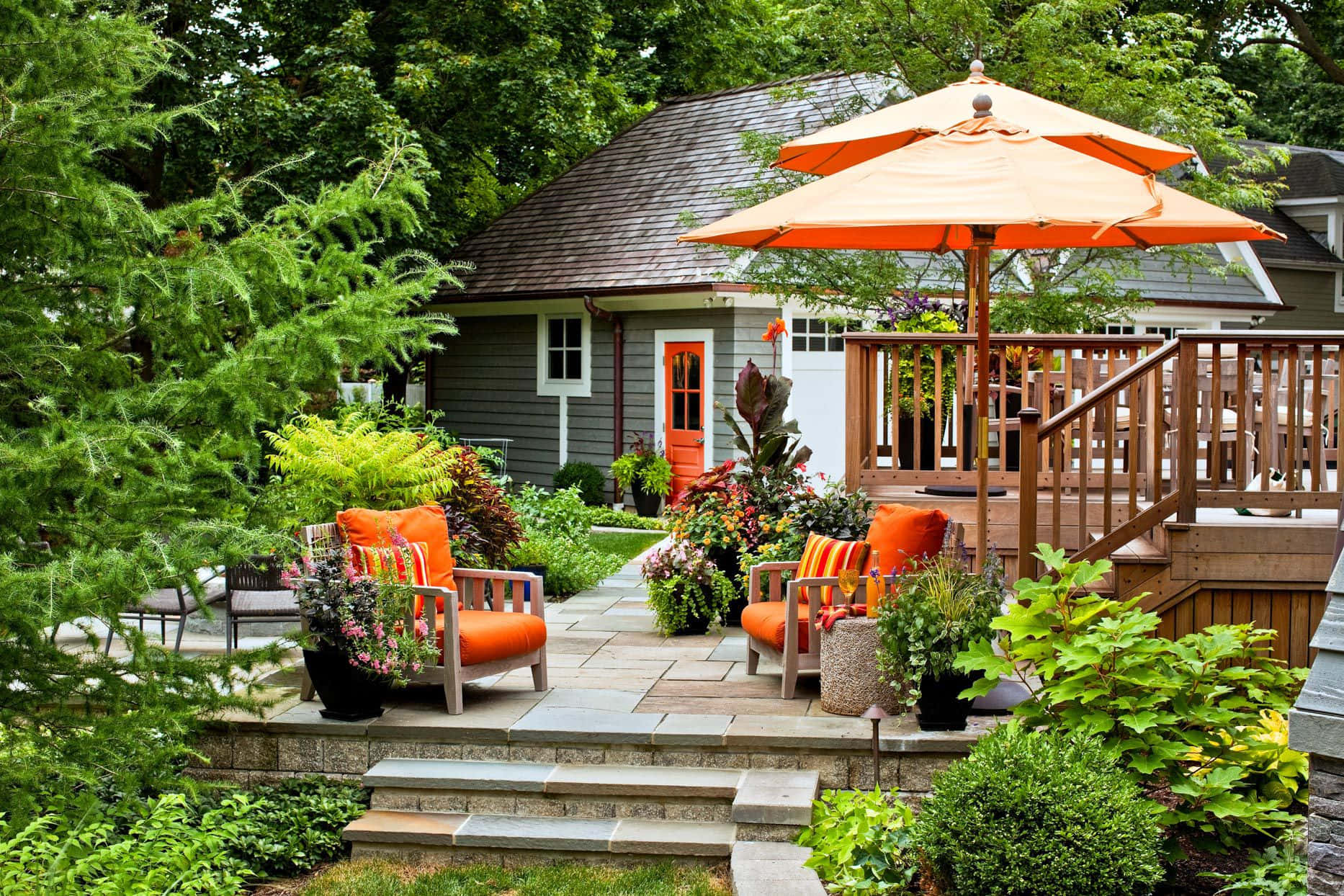 A Backyard With Orange Furniture And An Umbrella