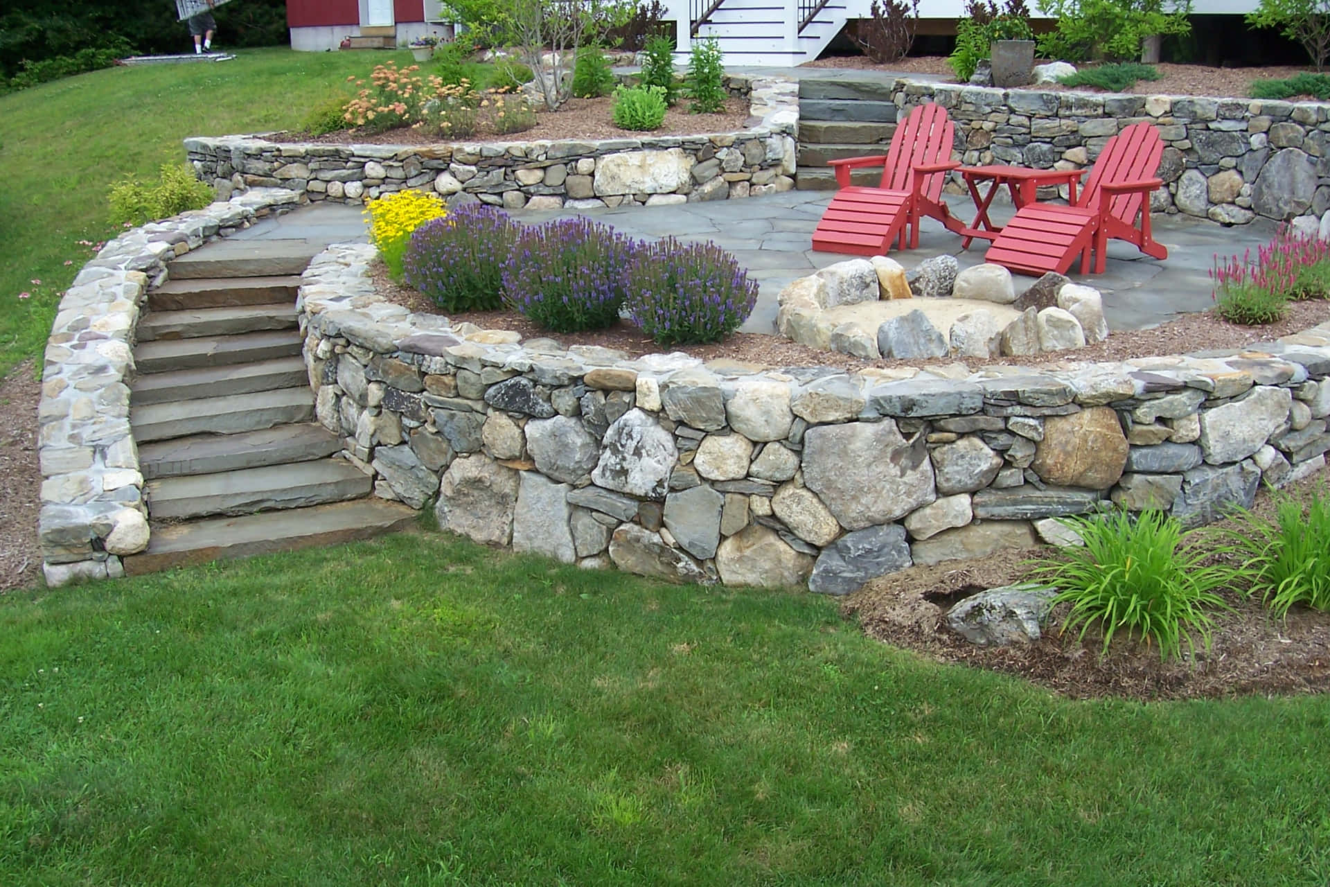 a stone wall with a rock garden and chairs