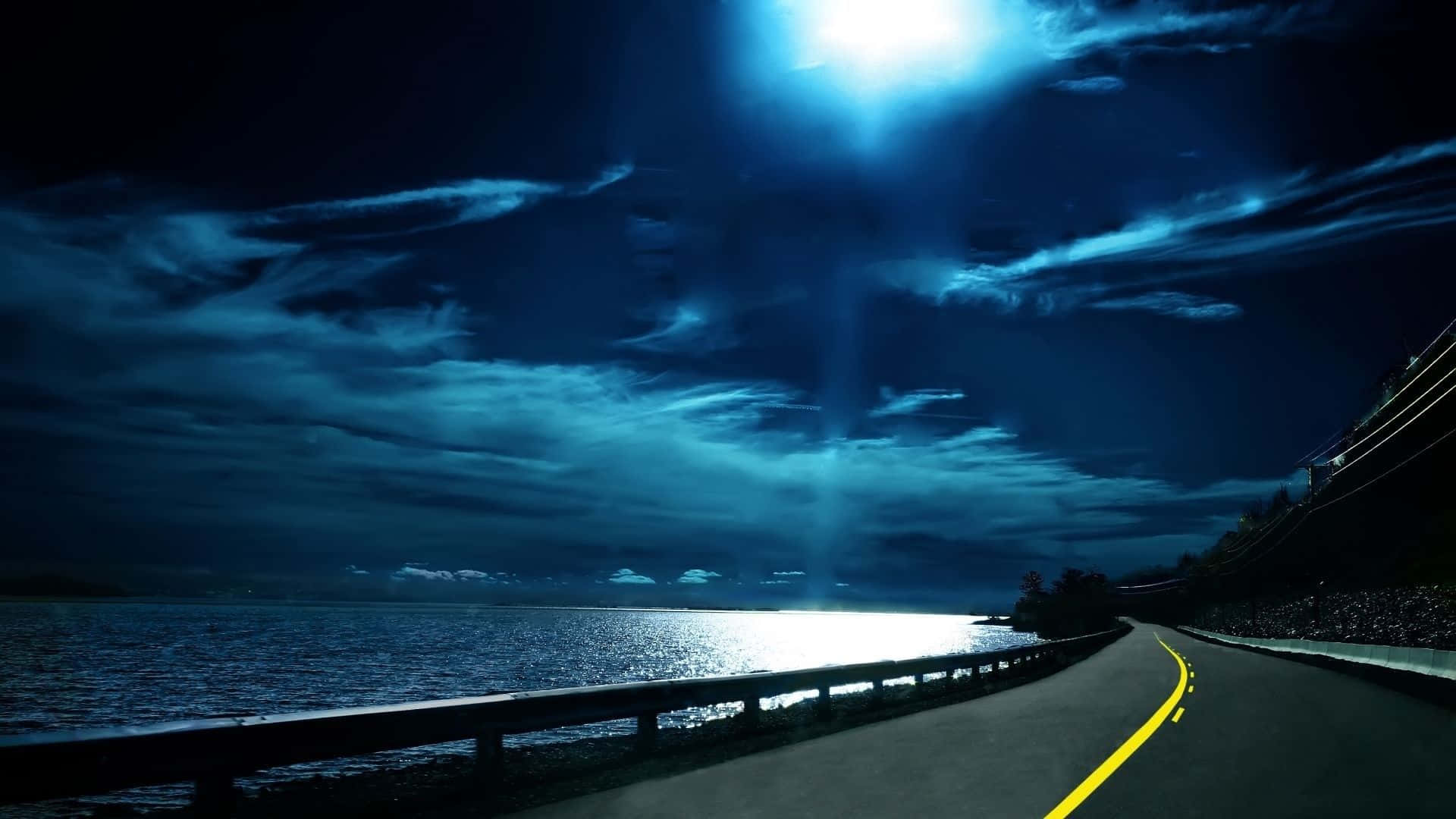 A Road With A Bright Moon Shining Over The Water Wallpaper