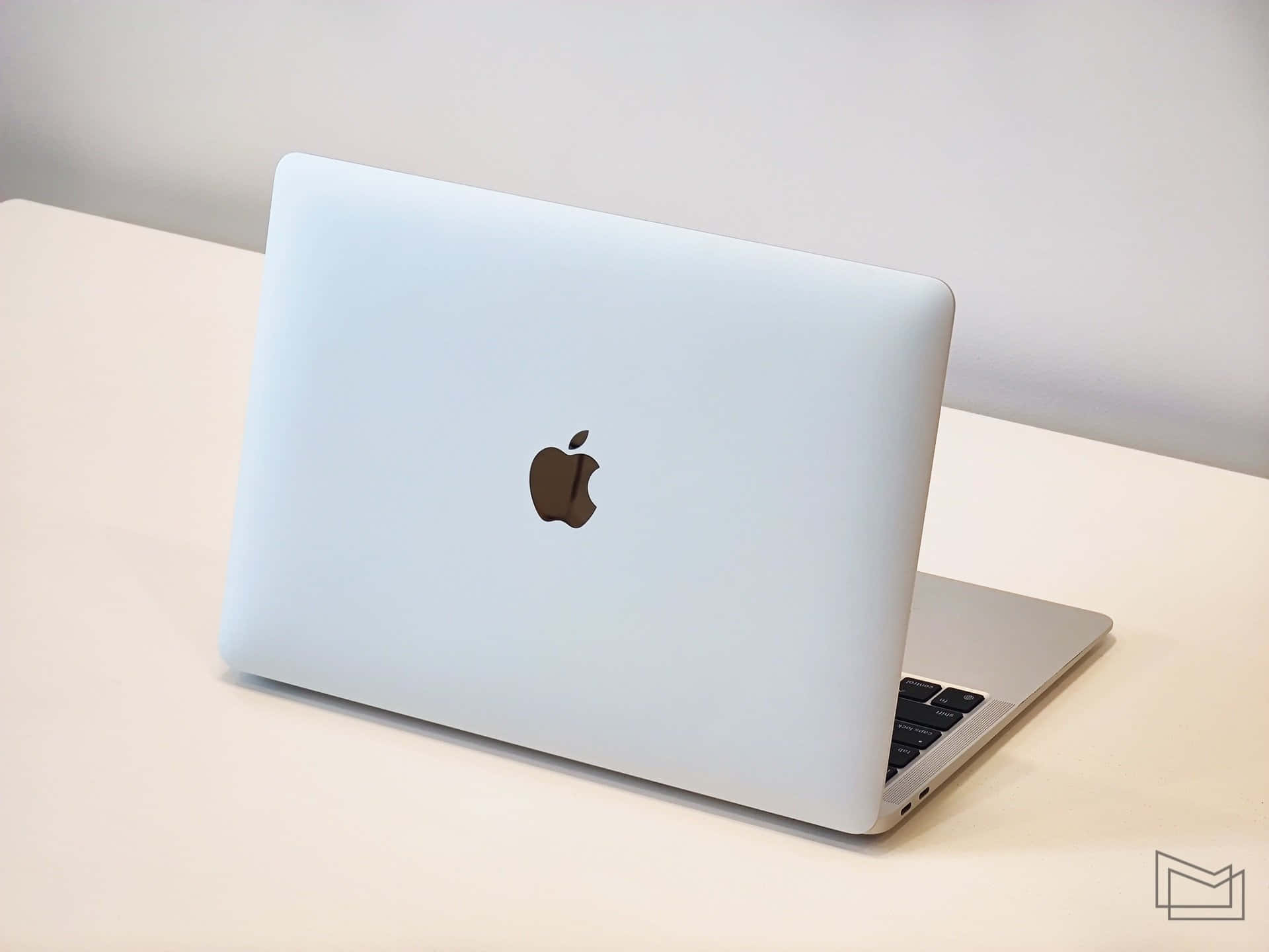Download A White Macbook Pro Laptop Is Sitting On A Table | Wallpapers.com