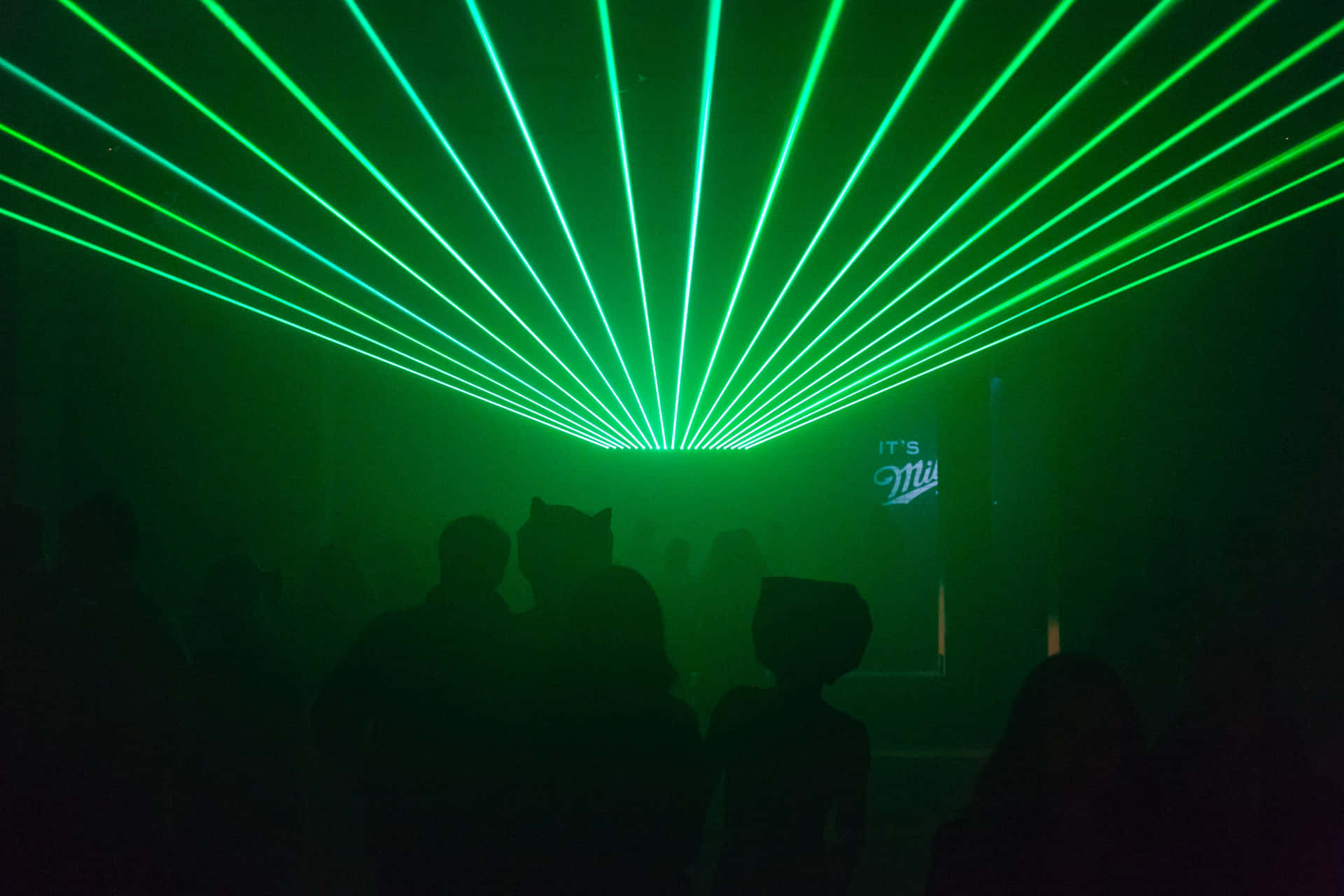 A Group Of People Standing In Front Of A Green Laser Light