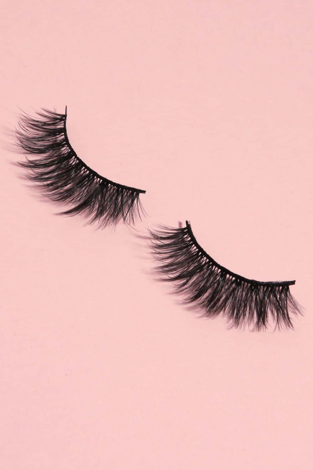 A Pair Of False Eyelashes On A Pink Background