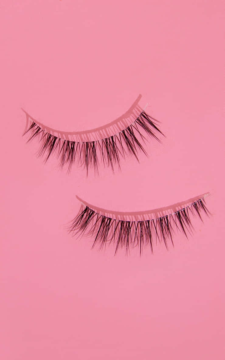 Two False Lashes On A Pink Background