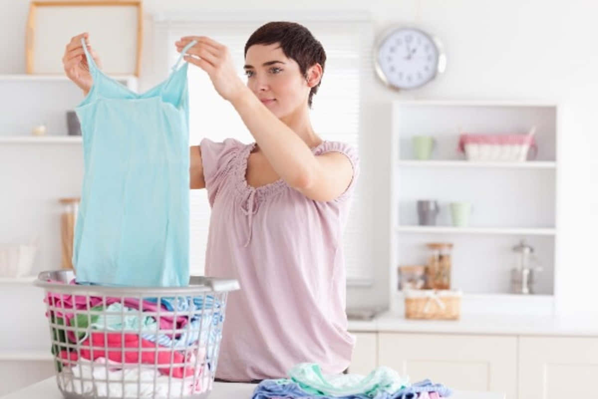 Kvinnalägger Kläder I En Tvättkorg