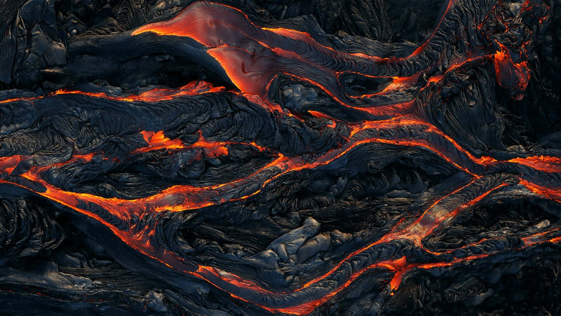 Red hot molten lava oozing through a black and grey rocky surface