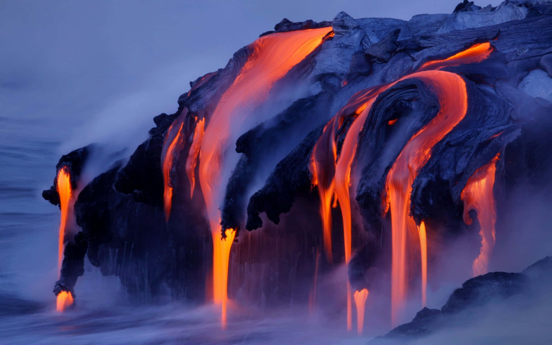 A volcano erupts and streams of molten lava spill out