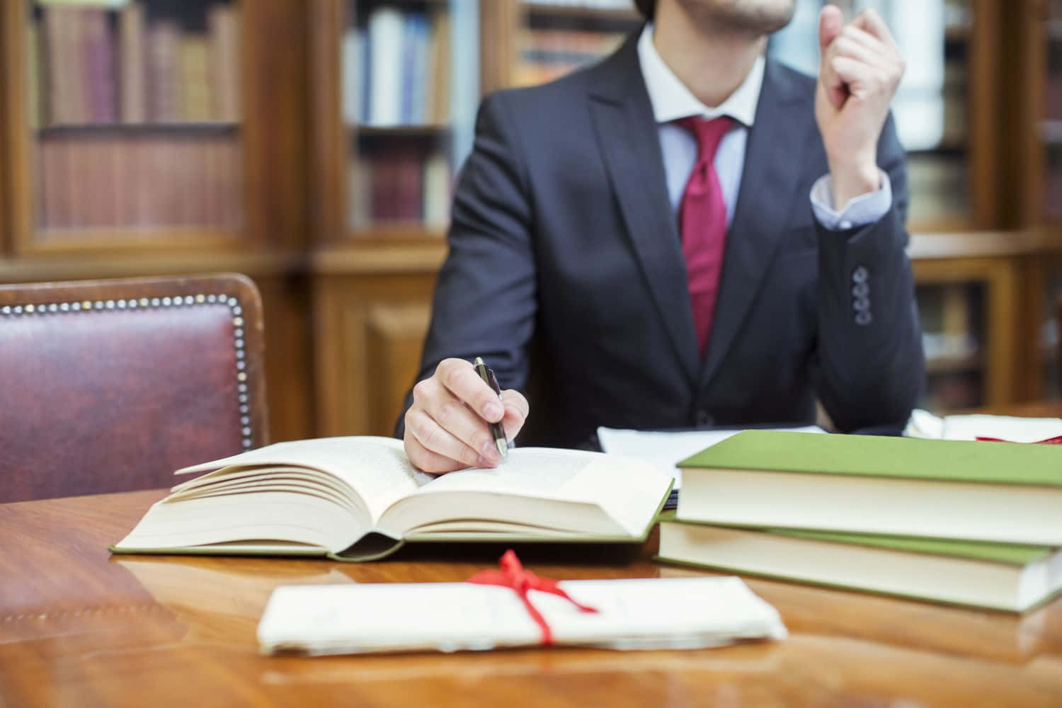 A Man In A Suit Sitting At A Desk With Books Wallpaper